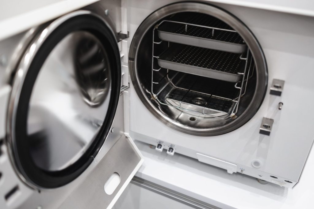 A dryer standing open with a drying rack fitted inside the drum