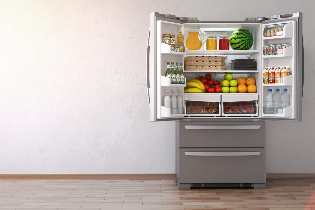 A French-door refrigerator standing open on a stocked interior, two freezer drawers below