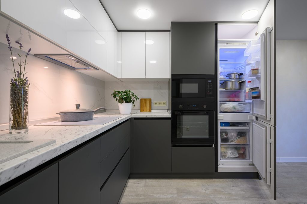 A grey handleless kitchen with the refrigerator column open at the end of the run