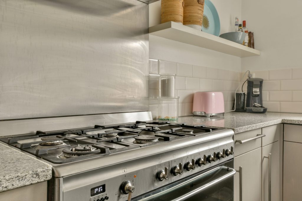 A stainless six-burner range with its oven below, set into a granite counter run